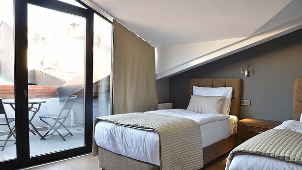 Un dormitorio con cama, mesita de noche, ventana con cortinas y vistas al exterior.