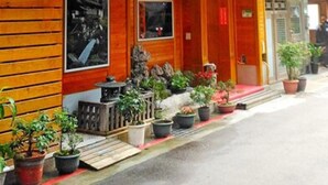 A traditional wooden building with a tiled roof, potted plants, and a small garden area in front. - Yachuan Hotel (Taipei)