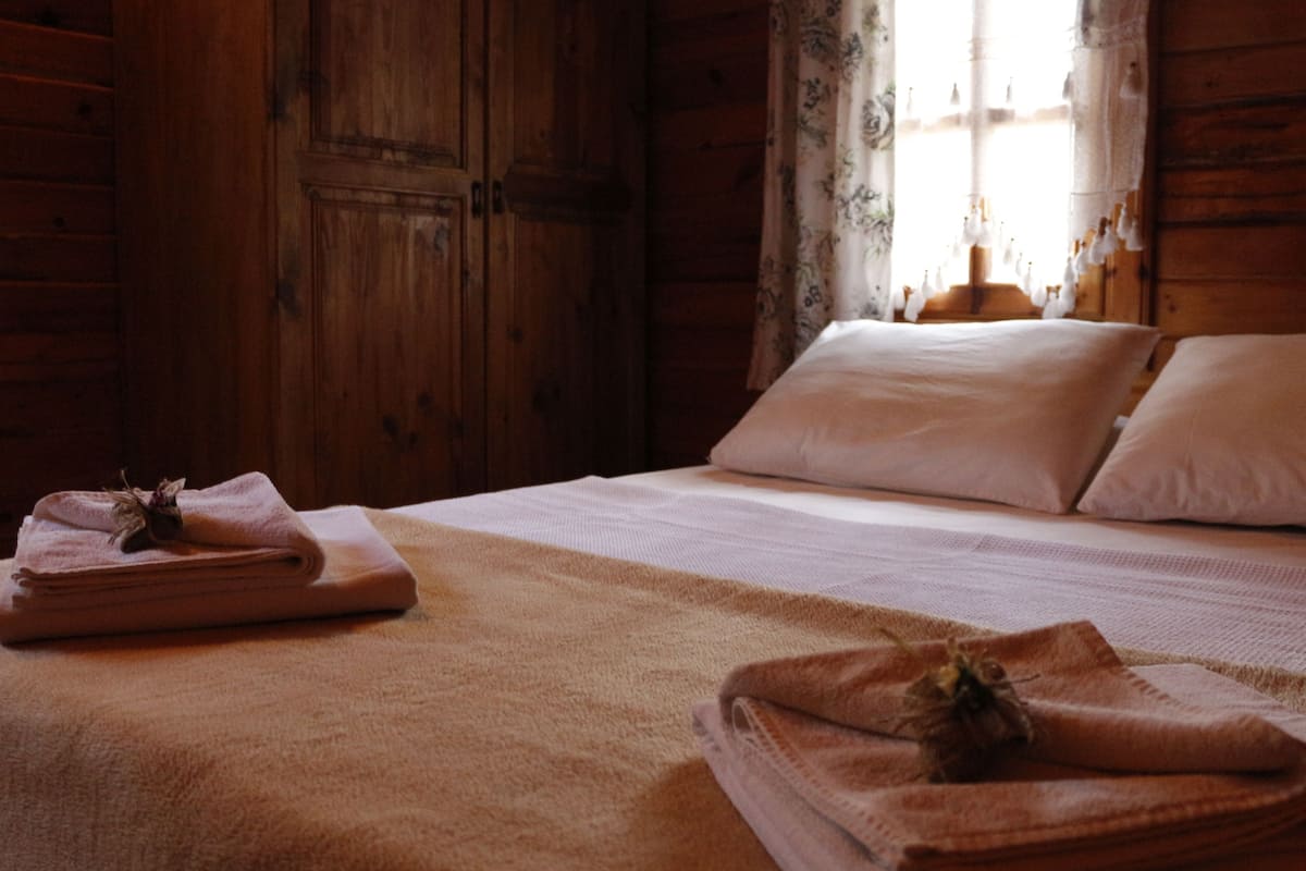 Una habitación de madera con una cama, almohadas y toallas dobladas.