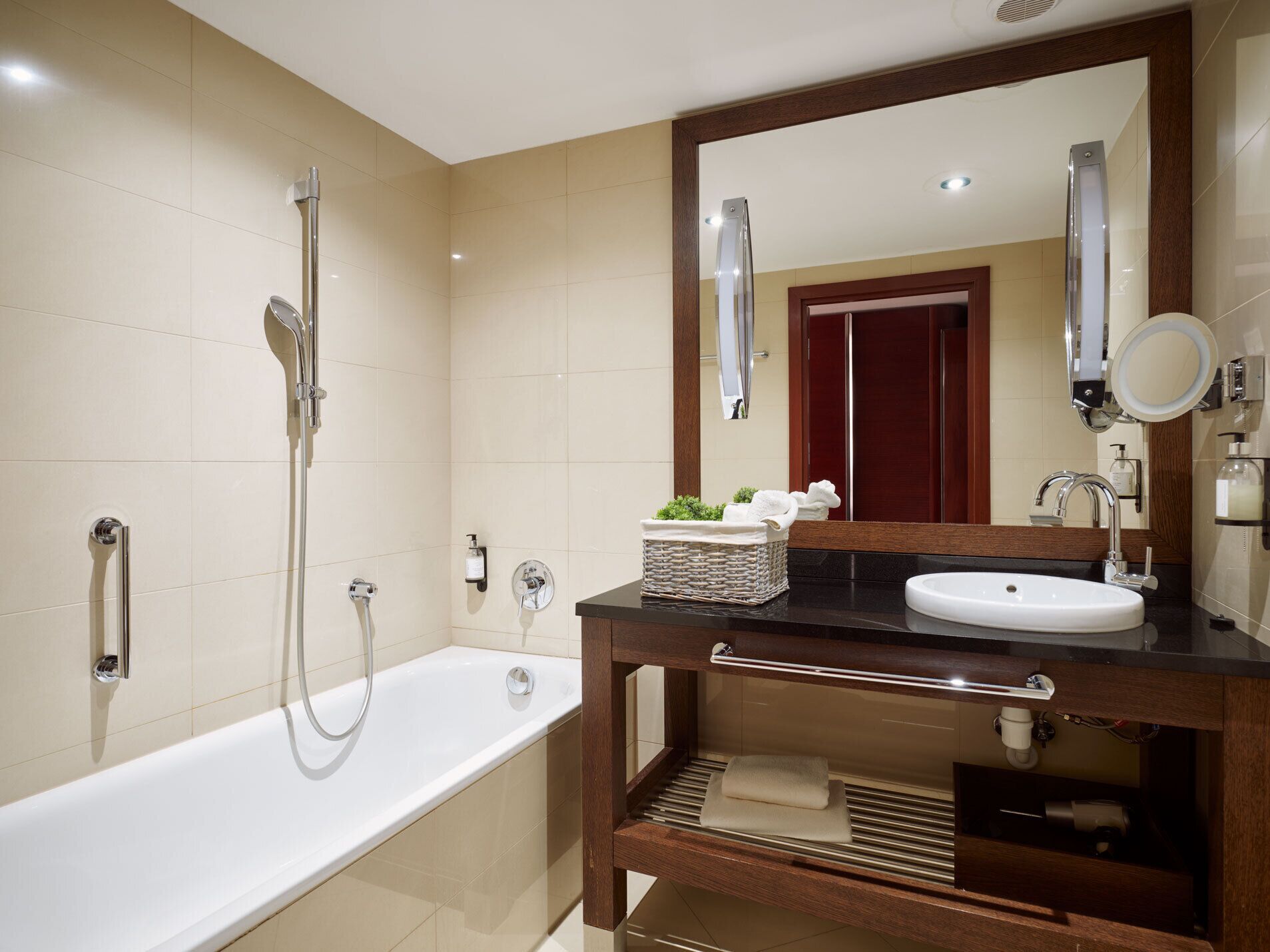 Un baño moderno con bañera, lavamanos y un espejo grande.