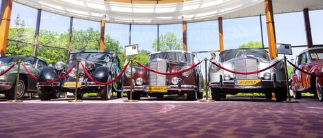 A car exhibition in a glass-roofed pavilion with vintage cars on display.