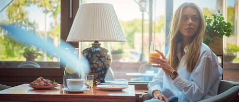 Iemand zit aan een tafel met een lamp, een glas sap en een bord eten.