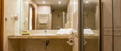 A bathroom with a sink, mirror, towel rack, and shower area.