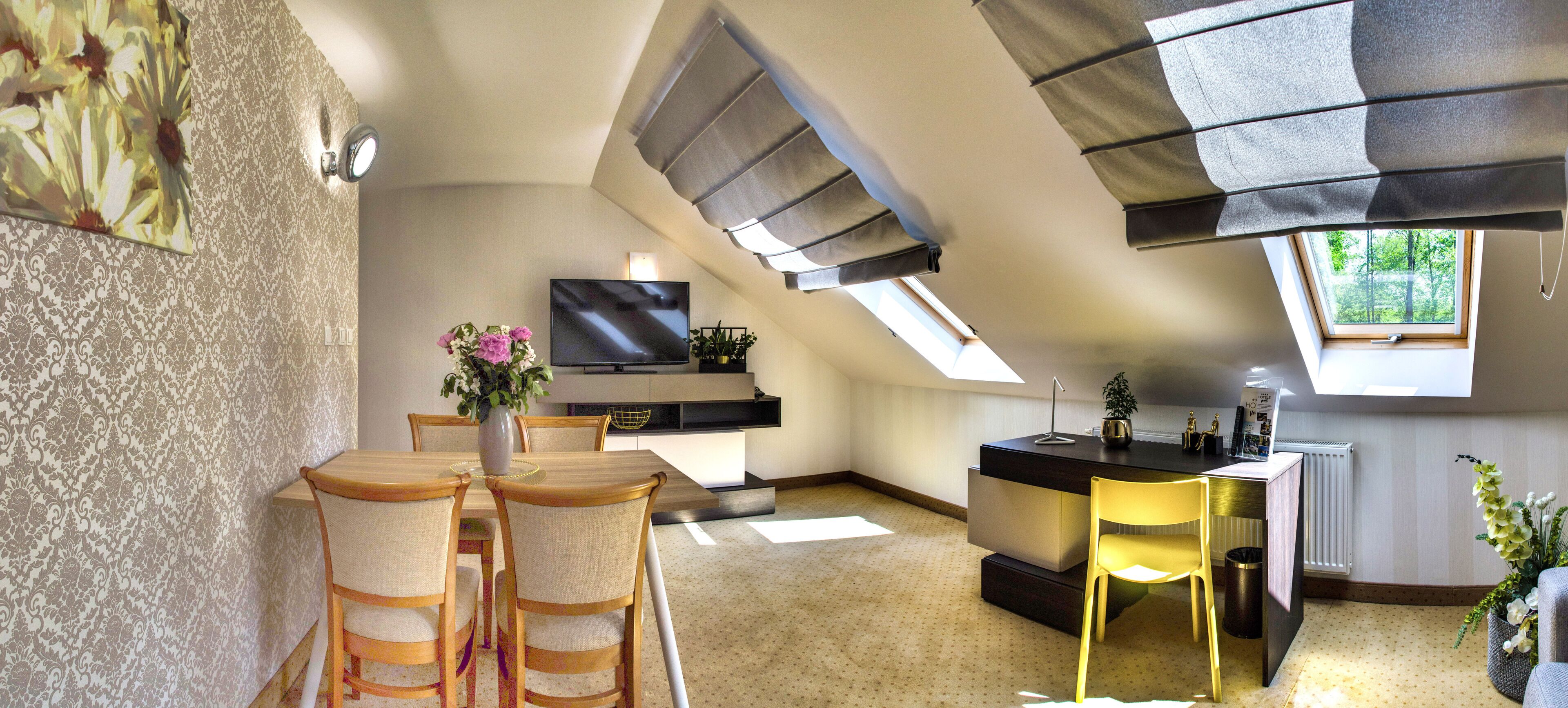 A modern kitchen with a TV, dining area with chairs, and a skylight.