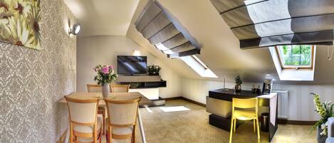 A modern kitchen with a TV, dining area with chairs, and a skylight.