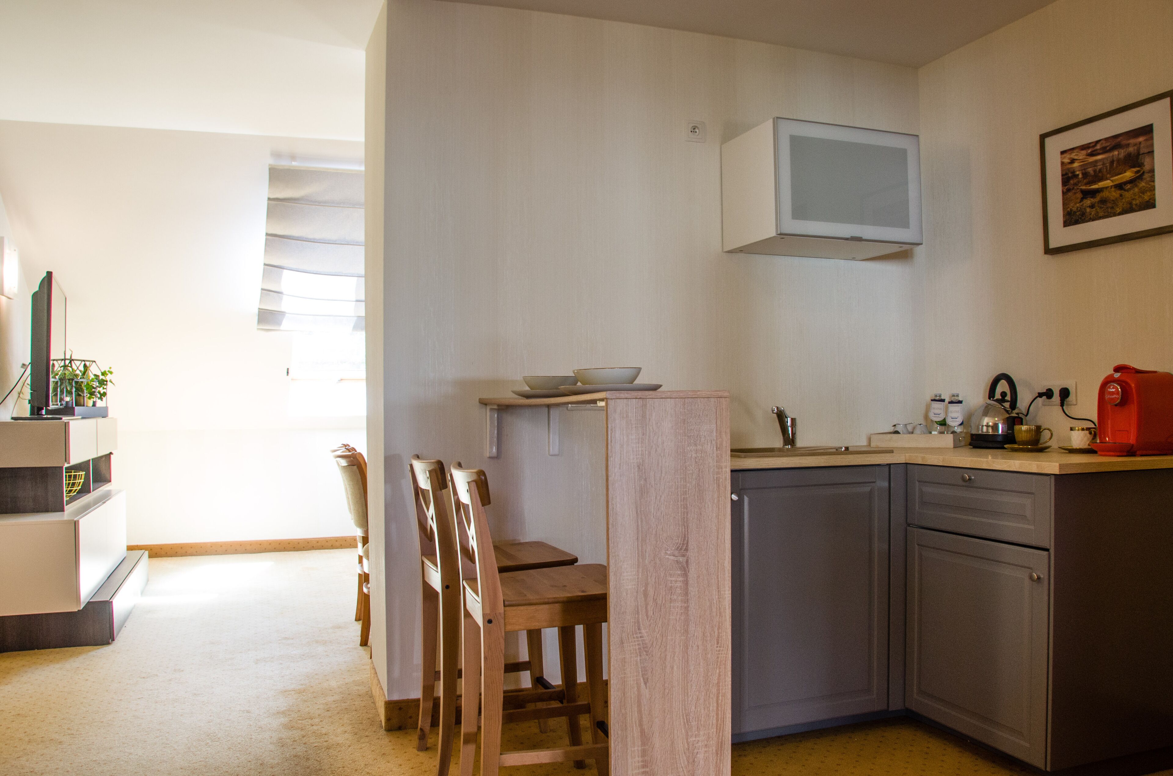 A compact kitchen with a dining area, a built-in microwave, and a coffee machine.