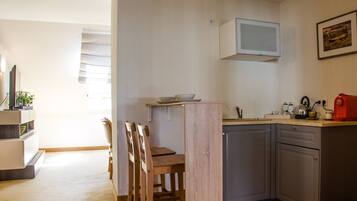A compact kitchen with a dining area, a built-in microwave, and a coffee machine.