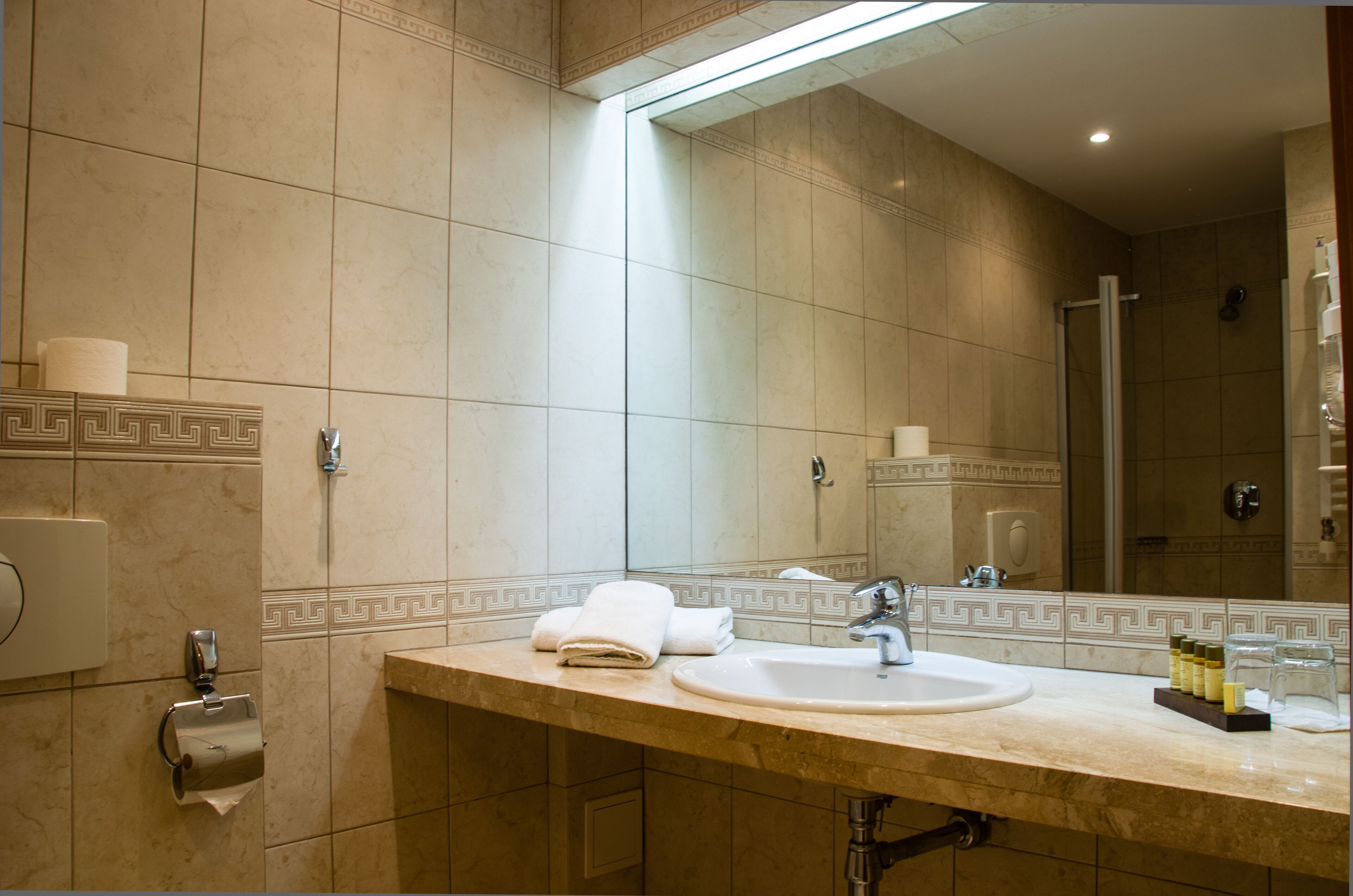 Een badkamer met een wastafel, spiegel en douche.