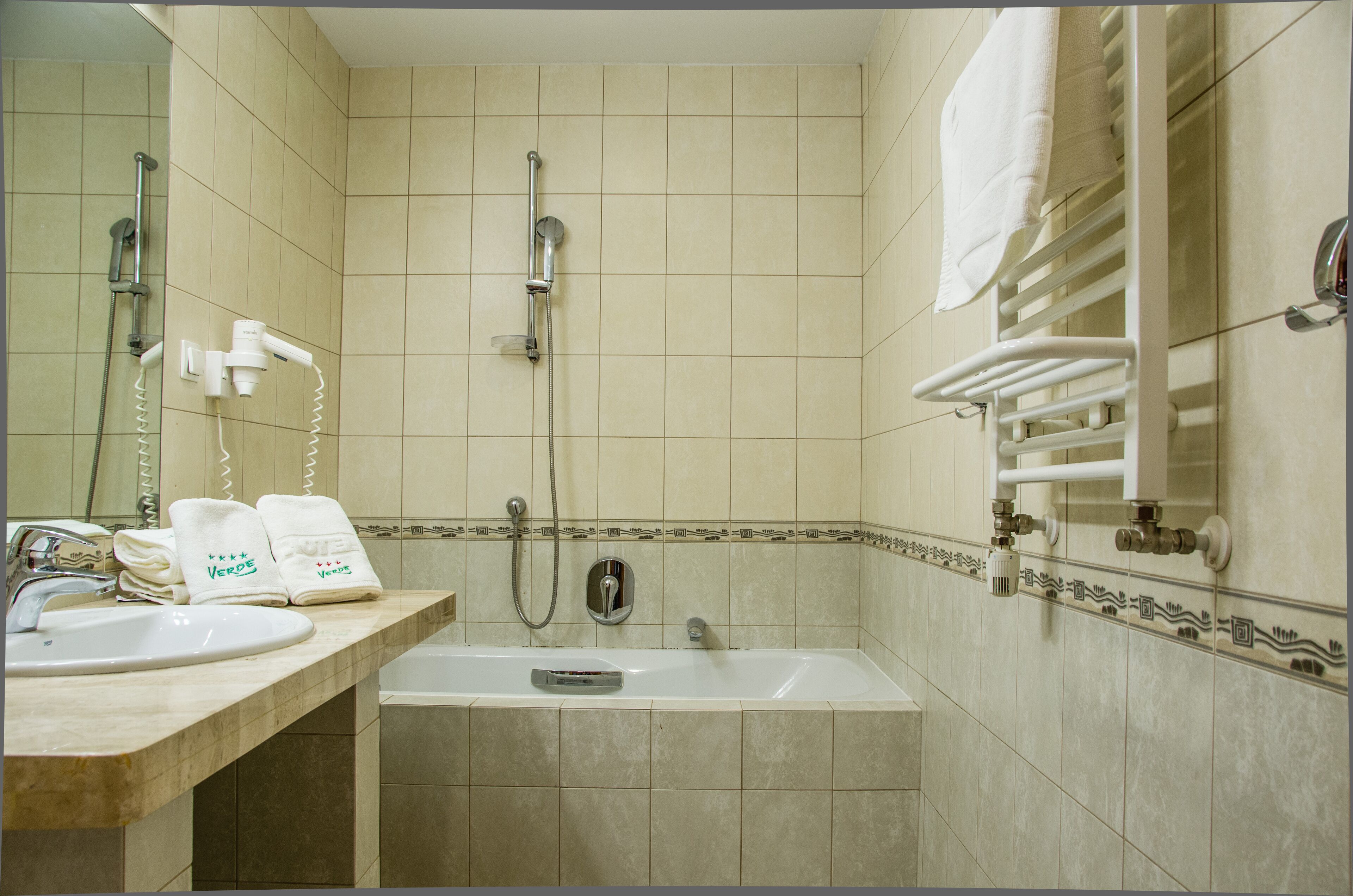 A bathroom with a sink, mirror, towel rack, shower, and bathtub.