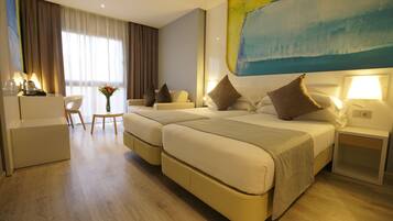 A hotel room with two beds, a desk, a chair, and a large abstract painting on the wall.