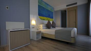 A modern hotel room with a bed, bedside table, lamp, and a painting on the wall.