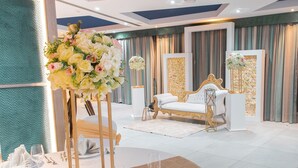 Une chambre luxueuse avec un canapé blanc, un miroir à cadre doré et un arrangement floral en guise de centre de table.