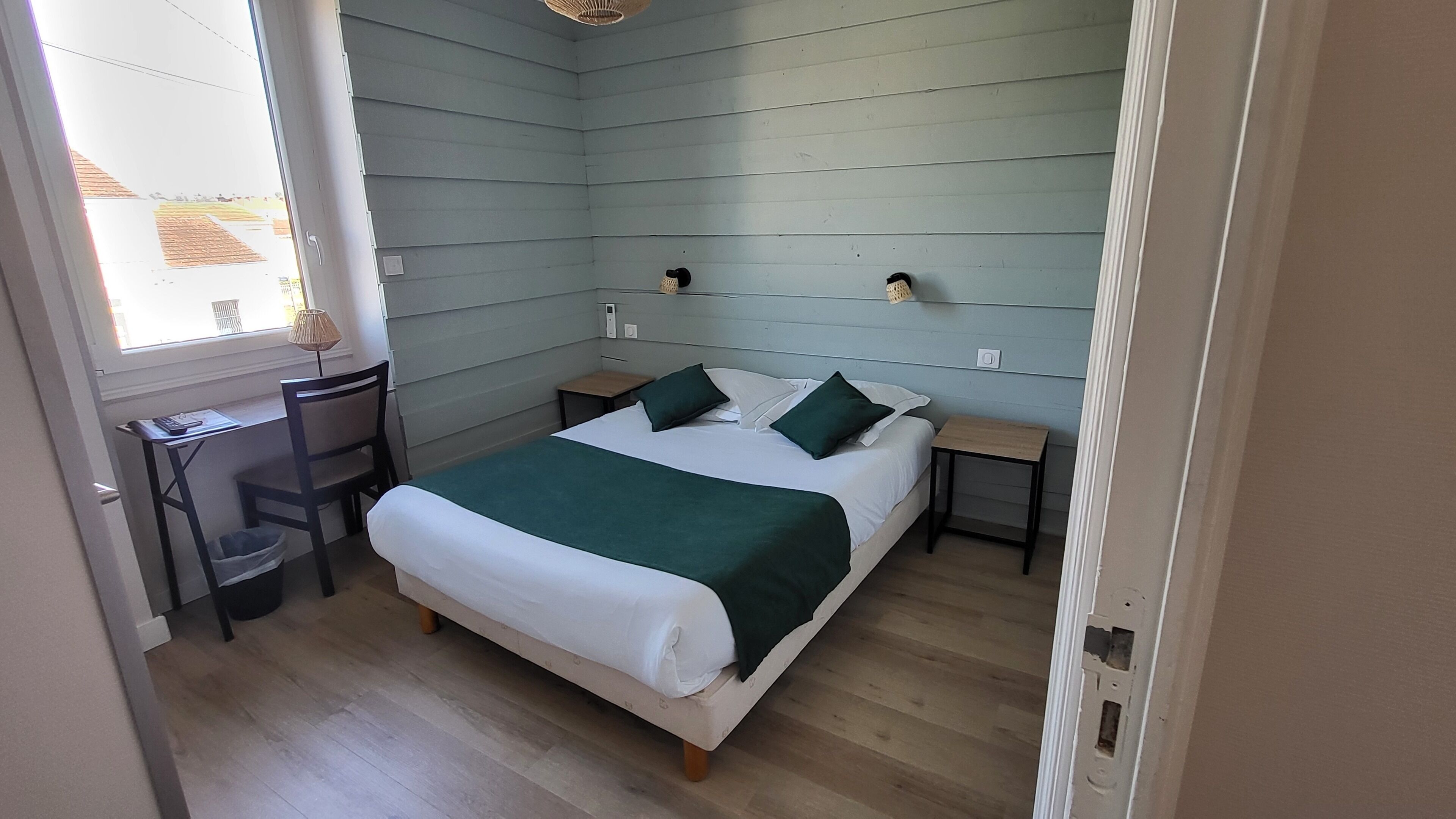 A bedroom with a bed, two bedside tables, a chair, and a small desk.