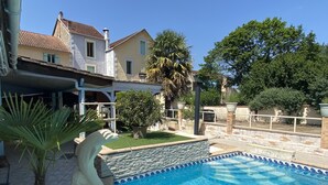 A swimming pool with a stone border and a decorative swan statue. - Hôtel Le RELAX (Boulazac-Isle-Manoire)