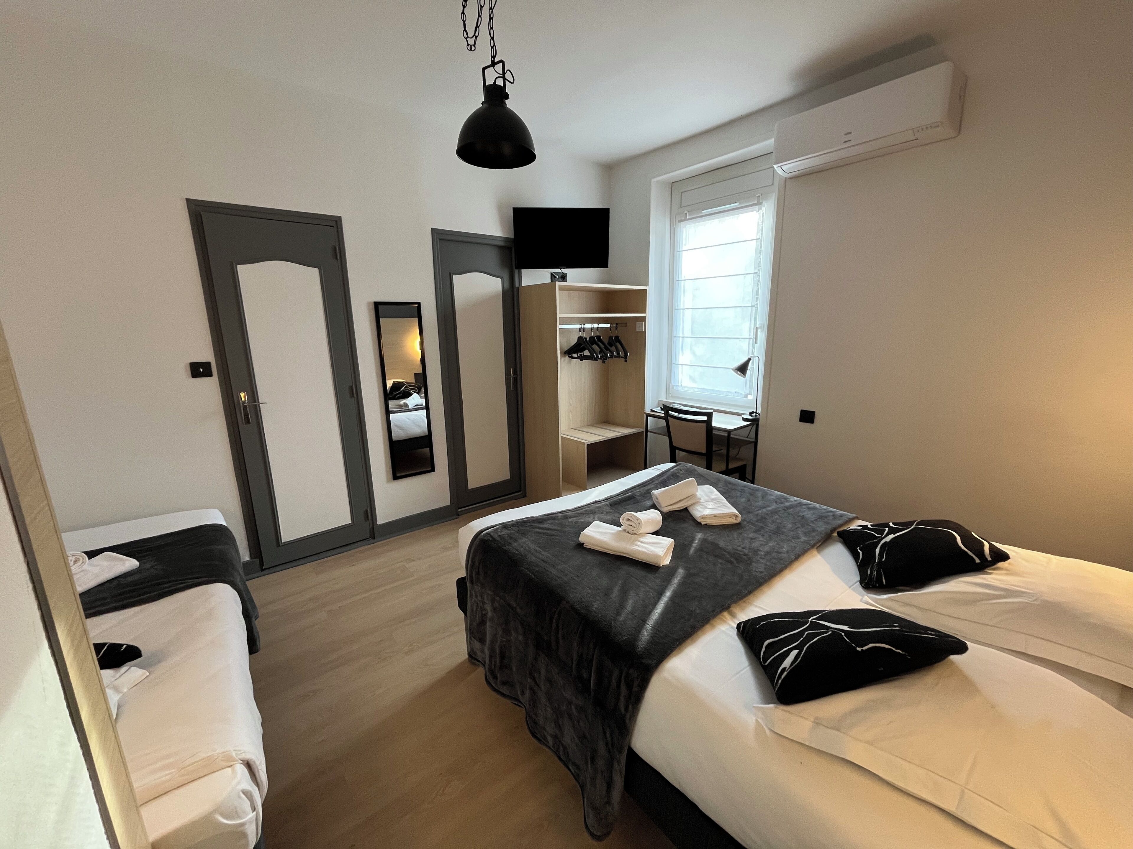 Una camera d'albergo con due letti, una scrivania, una sedia, una televisione e un armadio.