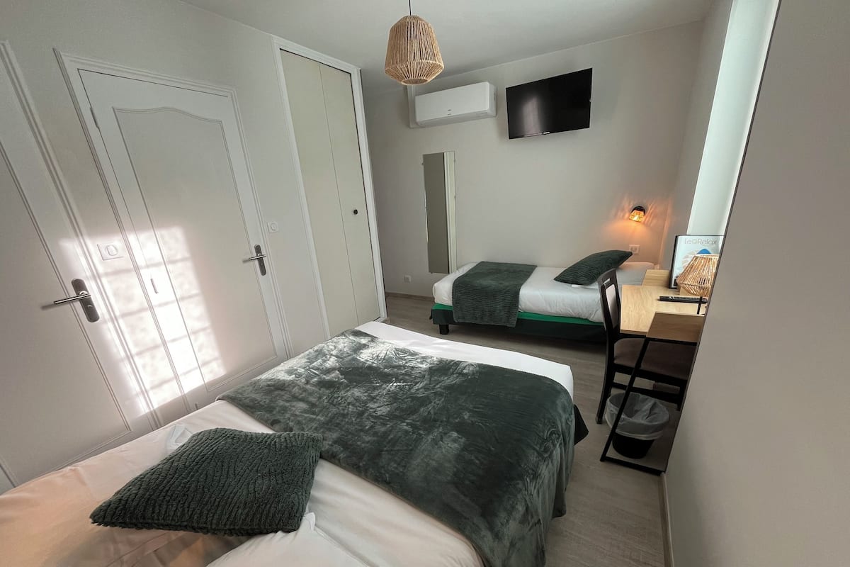 Un dormitorio con dos camas, un escritorio, una silla, un televisor y un armario.