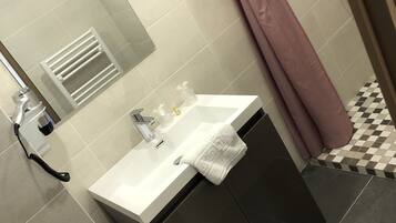 A bathroom with a white sink, dark cabinets, a mirror, and a shower with a pink curtain.