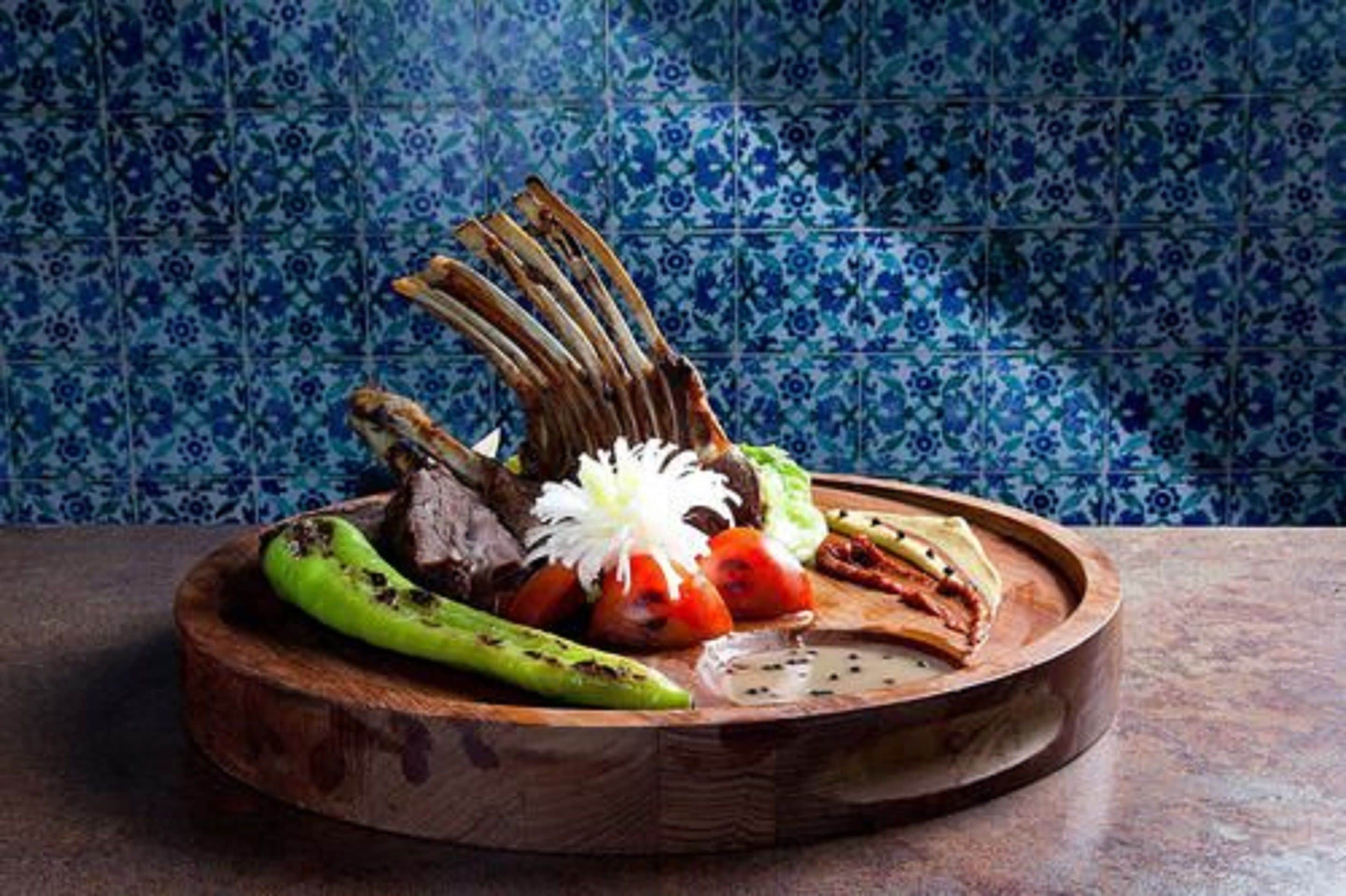 Une planche de service en bois, sur laquelle sont disposés divers aliments, notamment de la viande, des légumes et une fleur décorative.