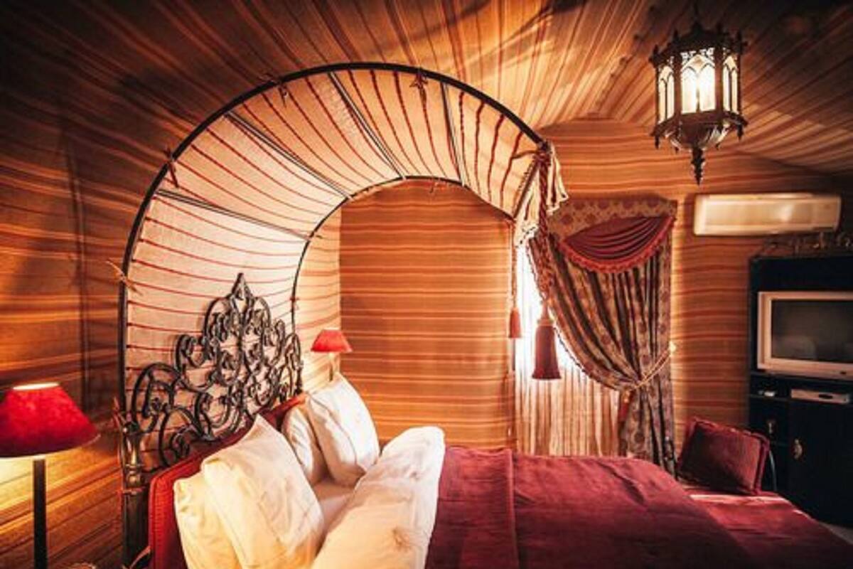 Un dormitorio con cama con dosel, televisión y una lámpara de pared decorativa.