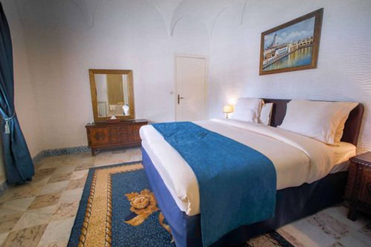 Un dormitorio con cama, cómoda, espejo, puerta y un cuadro en la pared.