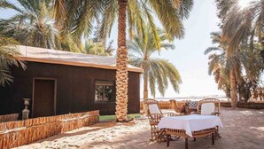 Una villa frente a la playa con zona de comedor que incluye mobiliario de mimbre y una mesa dispuesta para dos.