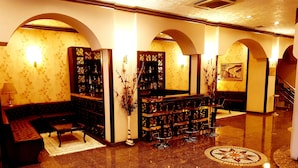 A lobby with a sofa, a coffee table, a bookshelf, and a decorative vase. - Business Park Hotel (Ankara)