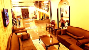 A lobby with a staircase, sofas, a coffee table, and a TV screen. - Business Park Hotel (Ankara)