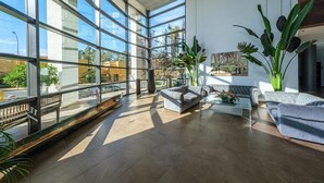 Een ruime lobby met grote ramen, een zithoek met banken en diverse kamerplanten.