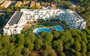 Un hôtel moderne doté d’une piscine centrale, de nombreux balcons et d’un jardin sur le toit.