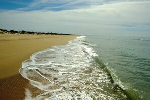 Een strand met een zandstrand en rustige golven.