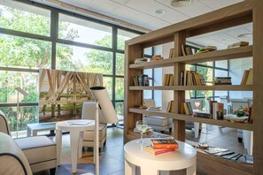 Een moderne bibliotheek met grote ramen, houten boekenkasten en een gezellige zithoek.