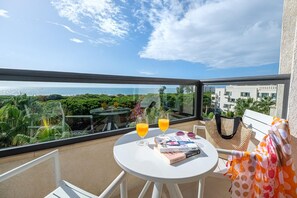 Un balcón con una mesa, dos bebidas, una revista y un bolso.