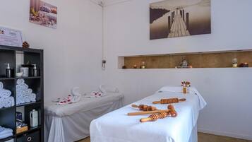 Un cuarto de spa con dos camillas, toallas e instrumentos de masaje.