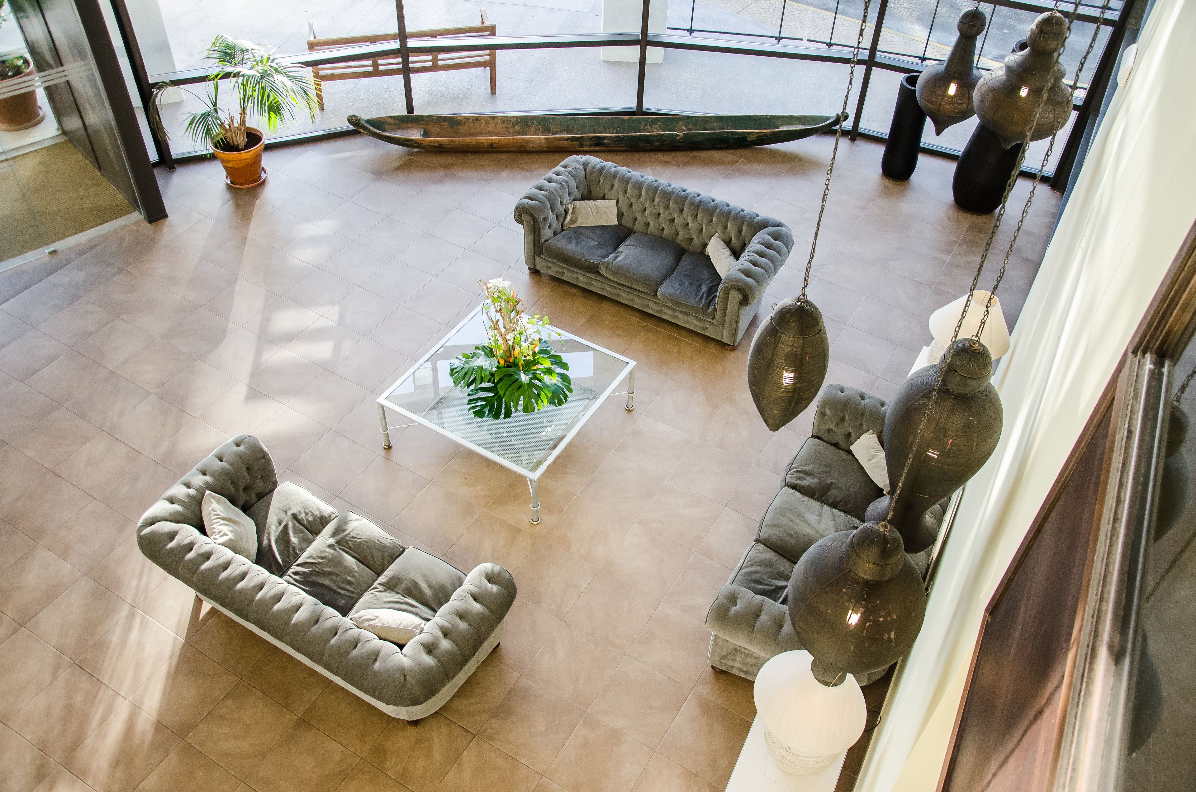 Amplia sala de estar con un sofá gris, un reposapiés a juego y una mesa de centro con una planta.