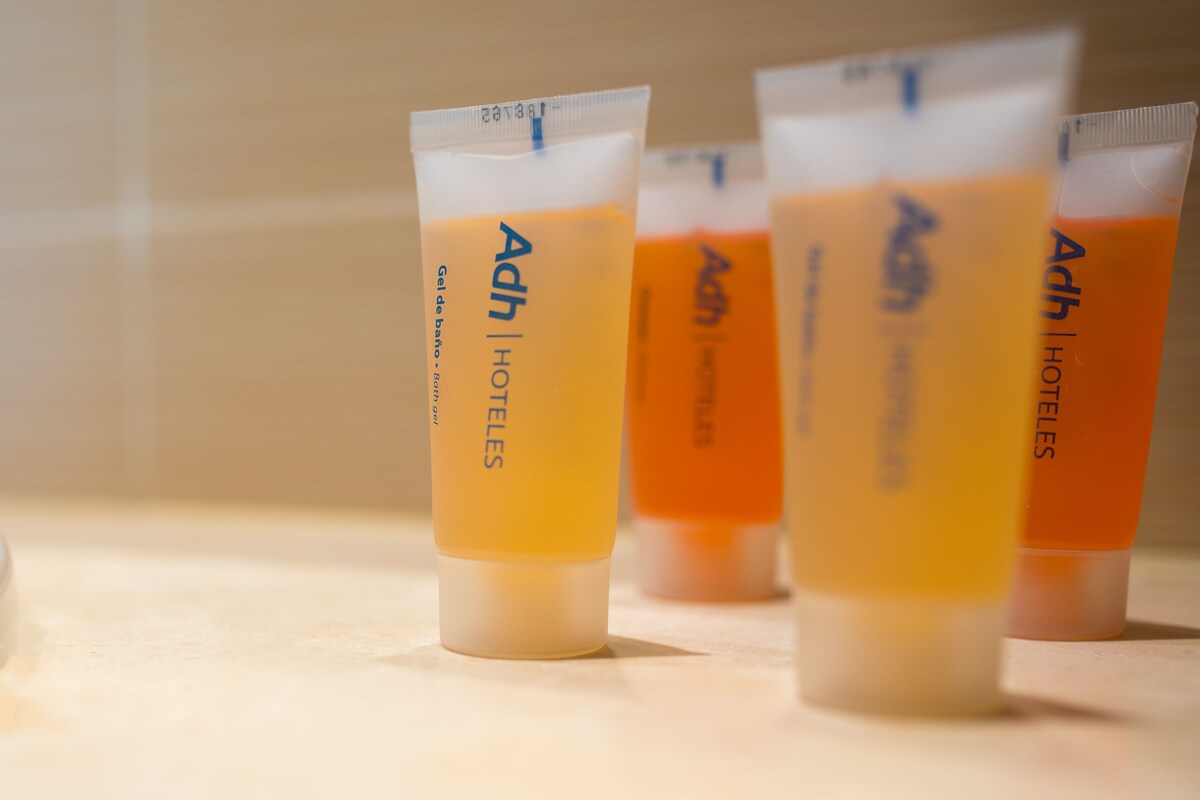 Vier tubes Adh hotel toiletartikelen op een aanrecht.