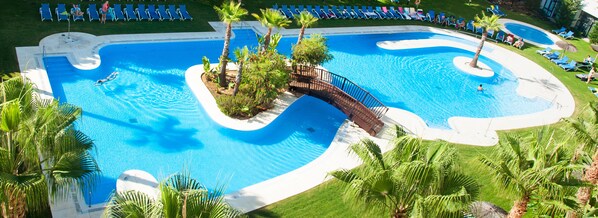 Alberca al aire libre, sombrillas en la alberca y camastros 