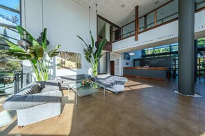 Een ruime lobby met een hoge plafond, modern meubilair en grote ramen met uitzicht op de omgeving.