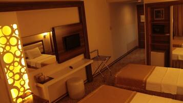 Habitación de hotel con cama, escritorio con televisor, espejo y un panel decorativo en la pared.