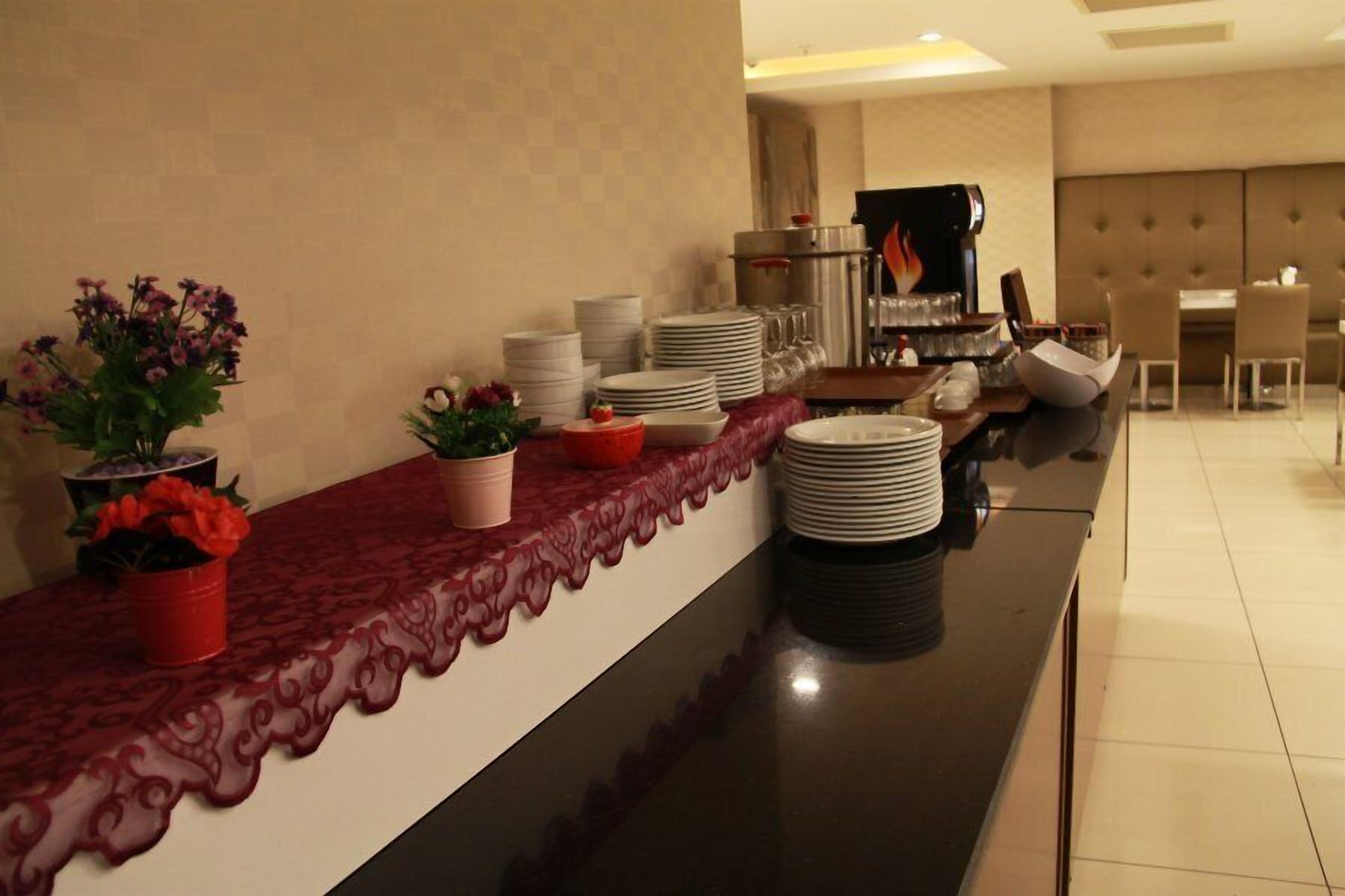 A buffet setup with a variety of dishes and drinks, a coffee machine, and a seating area in the background.