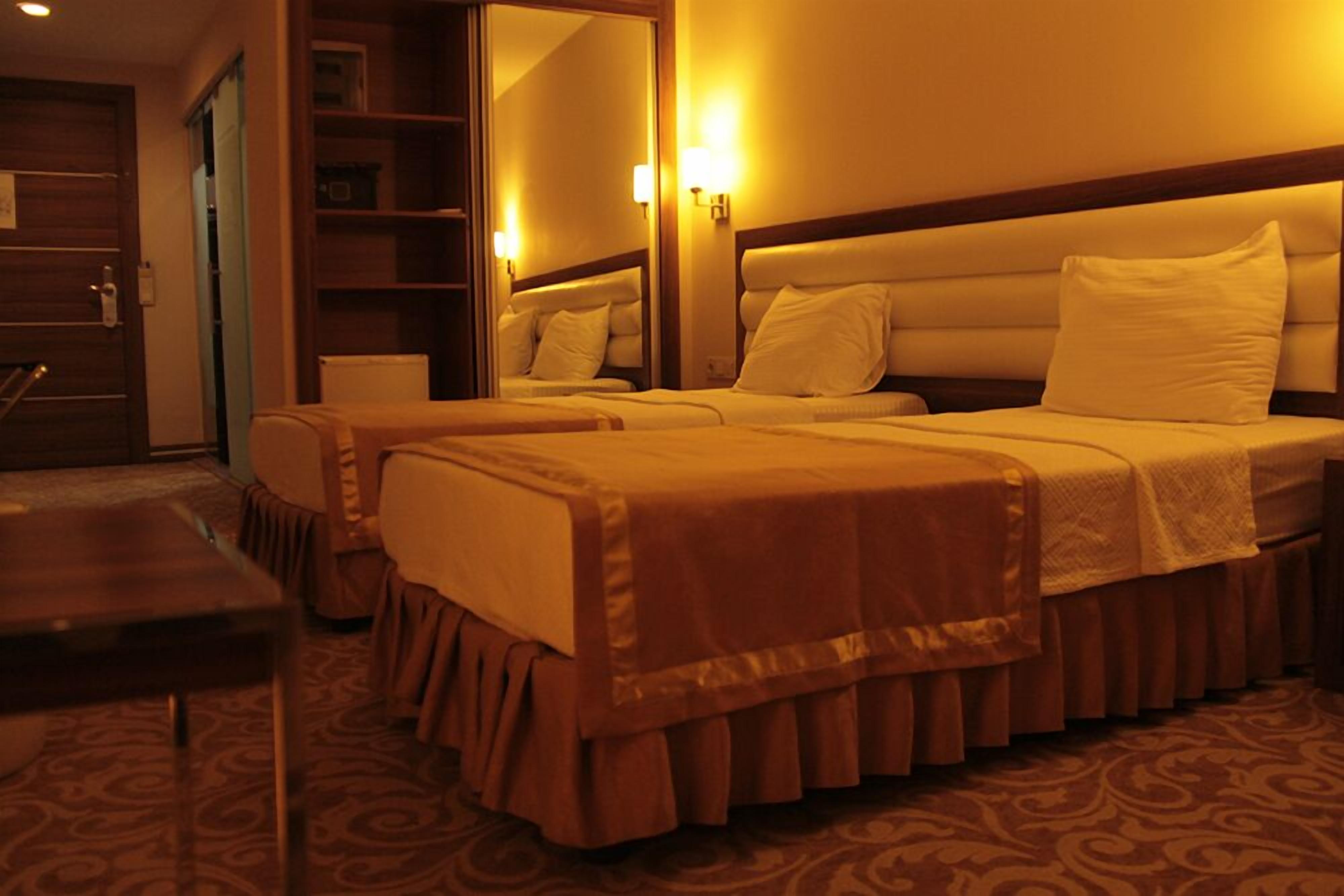 Habitación de hotel con dos camas, una puerta de madera, un espejo y una alfombra estampada.