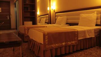 Habitación de hotel con dos camas, una puerta de madera, un espejo y una alfombra estampada.