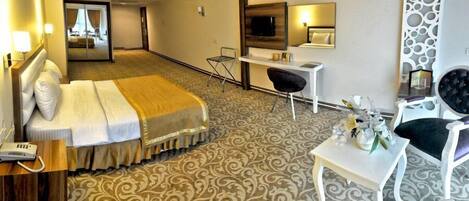 Una habitación de hotel con cama, escritorio, silla y una mesita con un jarrón de flores.