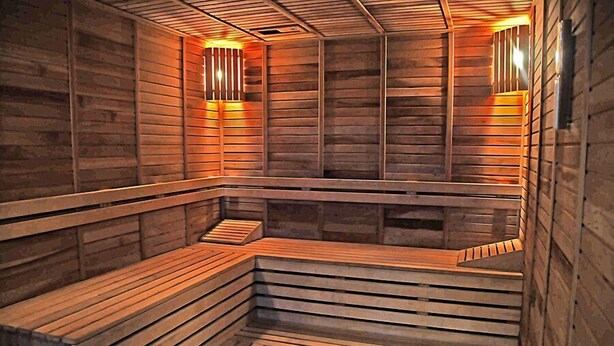 A sauna with wooden benches and slatted walls, featuring built-in lighting. - Ozpark Hotel (Aksehir)