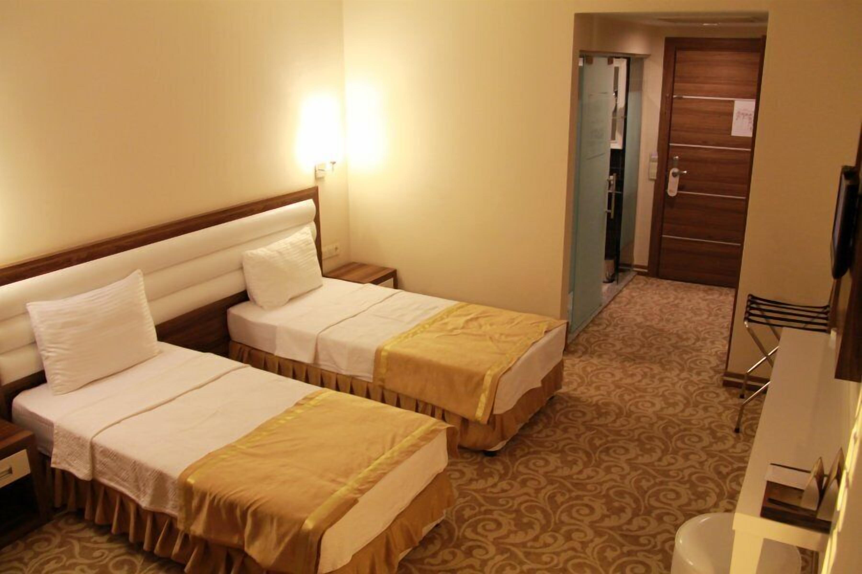 Une chambre d’hôtel avec deux lits, une table de chevet, une lampe, une armoire et une salle de bain.