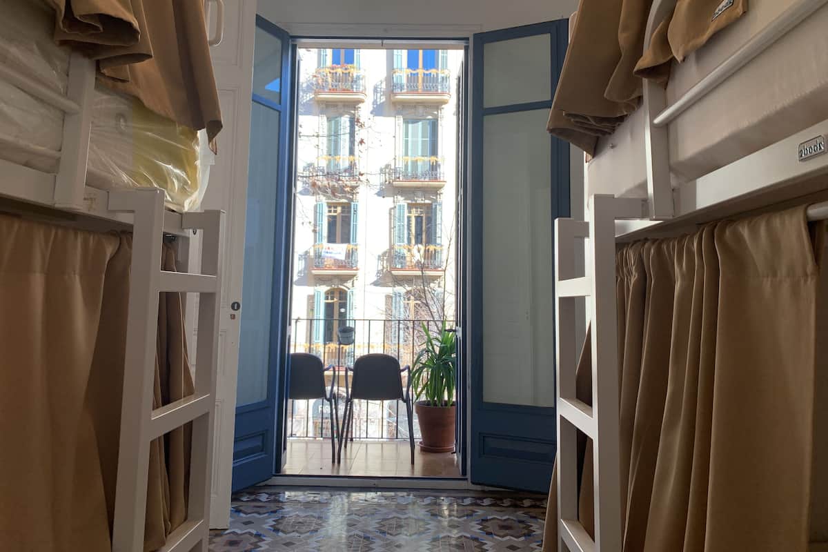 A narrow hallway with a view of a balcony and a potted plant.