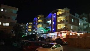 A multi-story hotel with balconies, a parking area, and a sign for a restaurant. - Ali Unal Apart Otel (Alanya)