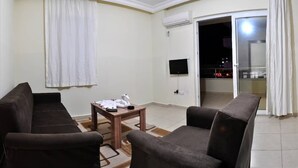A living room with two sofas, a coffee table, and a flat-screen TV mounted on the wall. - Ali Unal Apart Otel (Alanya)