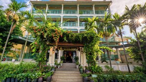 A hotel with a multi-story structure, a covered entrance, and lush greenery surrounding it. - Lantana Riverside Hoi An Hotel (Da Nang)