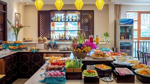A buffet with various food items and a bar area in the background. - Lantana Riverside Hoi An Hotel (Da Nang)