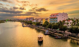 A riverside town with colorful buildings, a bridge, and boats.